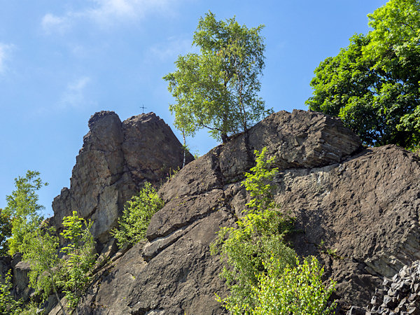 Stříbrný vrch with a prominent peak cross, located in the neighborhood of Zlatý vrch, shows horizontally lying basalt columns.