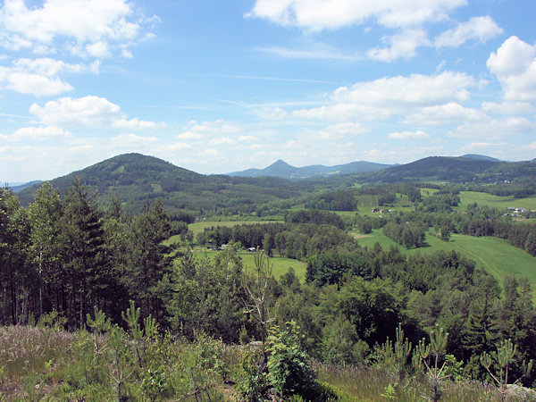 The lookout from the Jelení vrch hill to the west. In the foreground on the left side there is the Zelený vrch hill, on its right side the more distant Trávnický vrch hill and in the centre at the horizon there is the pointed Klíč hill.