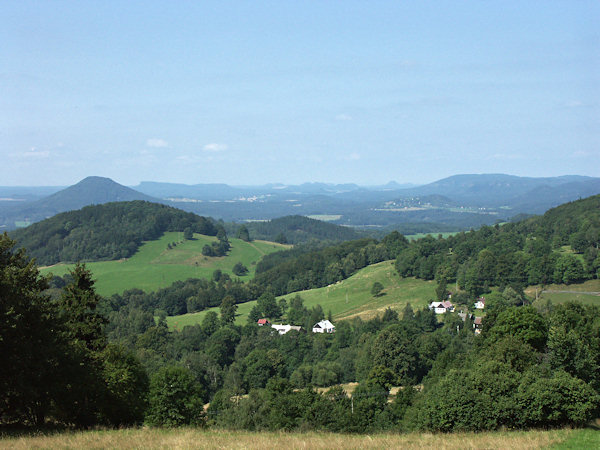 Blick vom Hang des Zlatý vrch (Goldberg) über Líska (Hasel) nach Westen. Links hinter dem Lipnický vrch (Himmertsberg) ist der auffallende Růžovský vrch (Rosenberg) und am Horizont die weiter entfernten Berge der Böhmischen und Sächsischen Schweiz, von denen der breite Grosse Winterberg rechts und der langgestreckte Tafelberg des Großen Zschirnsteins links auffällt. In der Mitte zwischen ihnen sieht man die Tafelberge der Umgebung von Königstein.