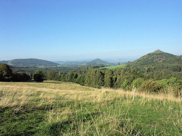 Aussicht von den Wiesen unter dem Ovčácký vrch (Schäferberg) nach Westen. Im Vordergrund rechts ist der Střední vrch (Mittenberg), im Hintergrund der Kegel des Zámecký vrch (Schlossberg) bei Česká Kamenice (Böhmisch Kamnitz) und links von ihm der langgestreckte Smrčník (Forst).