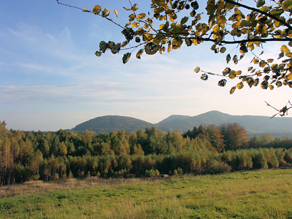 View from the hill foot of the hill Strážný vrch to the peaks surrounding the village Sloup. On the left side stands the rounded Šišák, to the right we see the peak of the Slavíček hill and behind it (in the centre) in the background the Tisový vrch hill is seen.