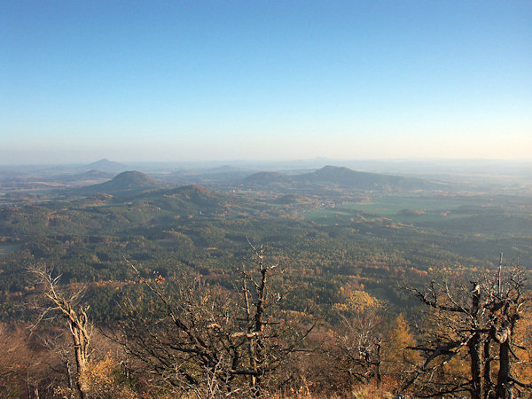 The outlook from the Klíč to the southeast into the surroundings of the village Sloup. The prominent hill on the left side is the Ortel with the lower hill Strážný in front of it, in the centre the elongated Šišák hill and on its right side the twins Tisový vrch and Slavíček. In the left part the Ralsko-hill rises from the horinzon.