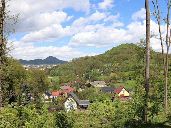 Skalice (Langenau)-Häuser zwischen den Hügeln Skalický vrch (Langenauer Berg) und Chotovický vrch (Kottwitzer Berg). Im Hintergrund sind Nový Bor (Haida) und Klíč (Kleis) zu sehen.
