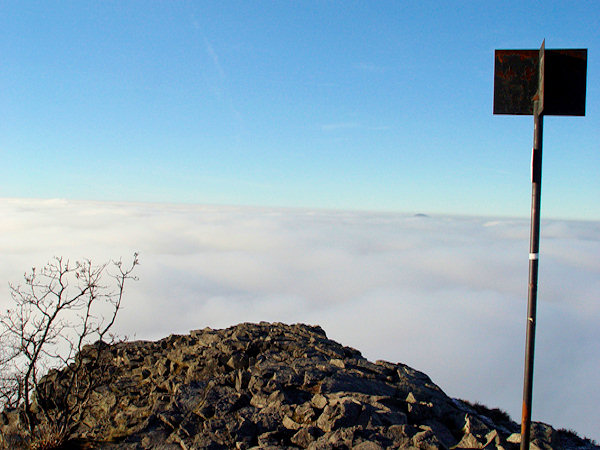 The rocky peak of the Klíč-Mt. protrudes over boundless masses of clouds.