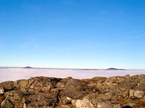 View from the peak of the Klíč-Mt. to the North: the surface of the masses of clouds is disturbed only by the distant peaks of the mountains Jedlová (left) and Pěnkavčí vrch (right).