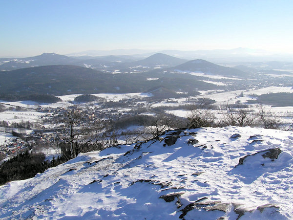 View from the peak of Klíč hill to the East in the foreground there is the village of Svor, behind of it the long Trávnický vrch with the prominent hill Hvozd with its two peaks in the background. In the right part of the picture there is the small town of Cvikov and behind of it the cones of the Zelený vrch hill and the higher Jezevčí vrch. On the horizon there is the Ještěd ridge (right) and the more distant Jizerské hory Mts.