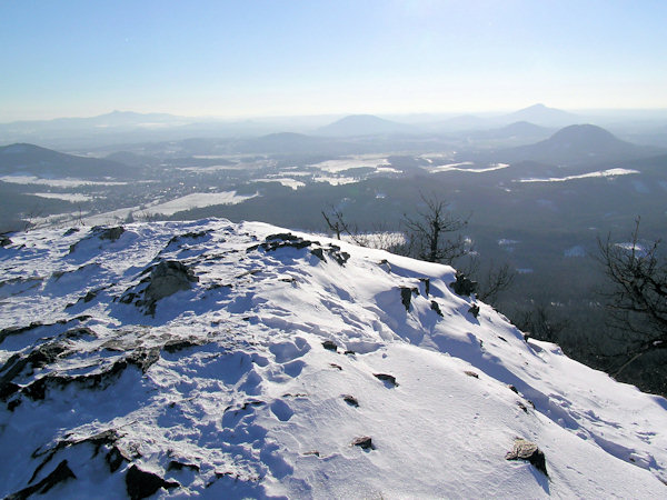 Outlook from the peak of Klíč hill to the Southeast: in the foreground to the right there is the bell-shaped Ortel hill, behind it the lower Brništský vrch hill and in the background the dominant peak Ralsko. In the centre of the picture there is the Tlustec hill with the lower Kovářský vrch in the foreground and quite to the left there is the town of Cvikov with the Zelený vrch hill. The distant horizon is closed by the prominent massiv of the Ještěd.
