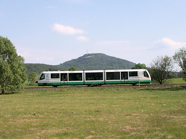 Osobní vlak z Liberce projíždí širokým údolím pod Jedlovou do své cílové stanice v Rybništi.