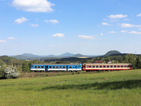 Osobní vlak do Rumburka vyjíždí na násep za svorským nádražím. Vpravo vyčnívá vrch Ortel, v pozadí uprostřed Ralsko a vlevo Tlustec s dobře patrným čedičovým lomem.