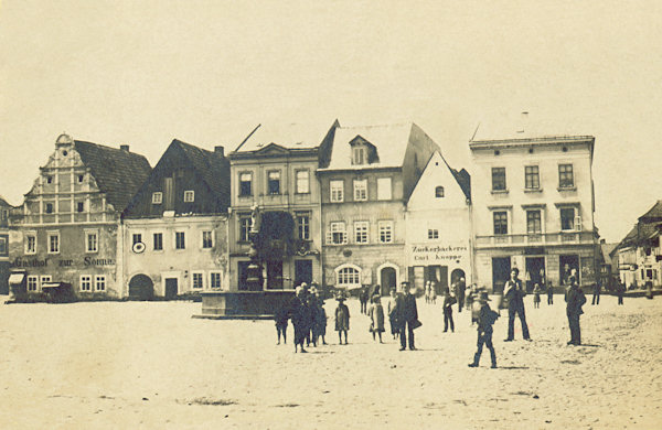 This postcard of Česká Kamenice from 1899 shows the view of the western side of the Market place before the reconstruction of the three gable-roofed houses. The same place after their reconstruction is on the next postcard from 1910.