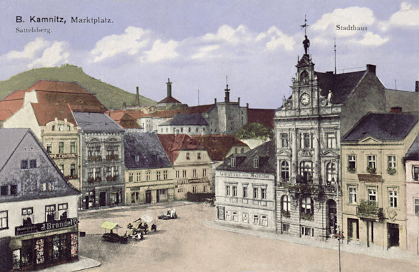 Diese Ansichtskarte von Česká Kamenice (Böhmisch Kamnitz) aus dem Jahre 1913 zeigt die Südwestseite des Marktplatzes mit dem Jugendstil-Hause der Sparkasse und das am Ende des 2. Weltkrieges vernichtete benachbarte Restaurant Zur Sonne. Im Hintergrunde sind die Gebäude der ehemaligen herrschaftlichen Bierbrauerei.