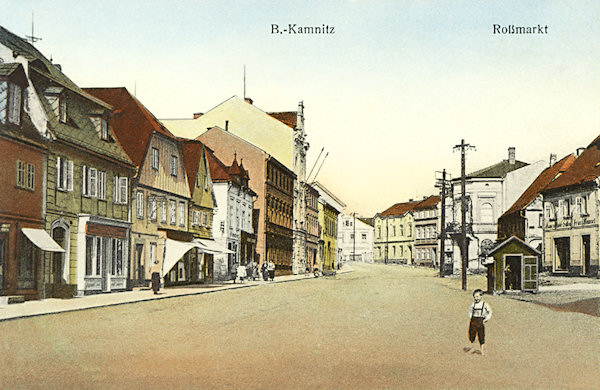 Diese Ansichtskarte zeigt den früheren Koňský trh (Rossmarkt) in der Oberen Vorstadt von Česká Kamenice (Böhm. Kamnitz). Unter den Häusern an der linken Seite ragt das im Sezessionsstil erbaute Gebäude der ehemaligen Bezirksvertretung aus dem Jahr 1907 hervor.