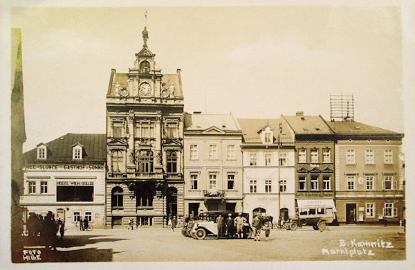 Na pohlednici západní strany náměstí vidíme výstavnou budovou spořitelny a vedle ní vlevo hostinec U Slunce s velkým oknem kavárny v 1. patře. V domě úplně vpravo bývala pošta.