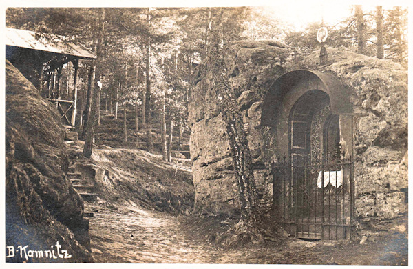 Pohlednice z doby kolem roku 1910 zachycuje skalní kapličku Nejsvětější Trojice pod Jehlou. Vlevo je vidět Münzelův přístřešek.