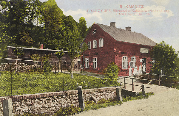 Na této pohlednici vidíme cihlový domek s pekárnou a koloniálem Franze Guseho, který stával u silnice kousek pod školou. Dnes na jeho místě stojí nový dům.
