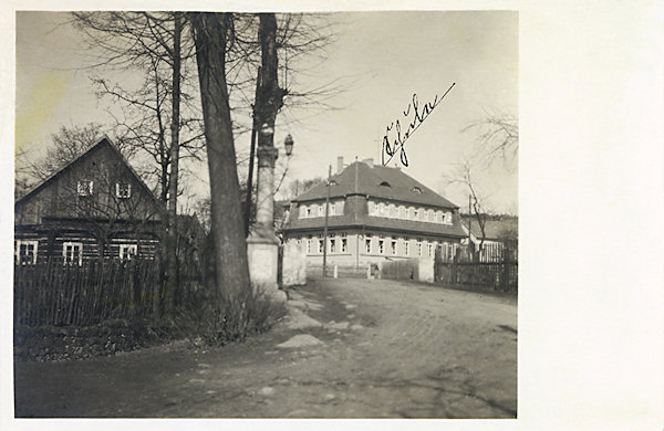 Auf dieser Ansichtkarte sieht man die Brücke im unteren Teil der Gemeinde mit der Statue des hl. Johann v. Nepomuk. Im Hintergrunde ist das Schulgebäude von 1925, das heute als Pension dient.