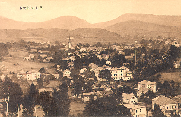 Diese Ansichtskarte von 1912 zeigt Chřibská gesehen aus dem Westen vom Pařez (Klötzerhöhe). Im Hintergrund ragt der Turm der St. Georgskirche hervor, hinter ihm am Horizont ist der Malý Stožec (Kleiner Schöber) und rechts von ihm der langgezogene Kamm des Velká Tisová-Berges (Grosser Eibenberg).