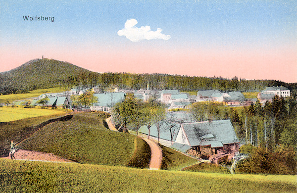 Diese Ansichtskarte zeigt die Gemeinde aus dem Süden. Im Hintergrund ist der Vlčí hora (Wolfsberg) mit seinem von einem Aussichtsturm gekrönten Gipfel.