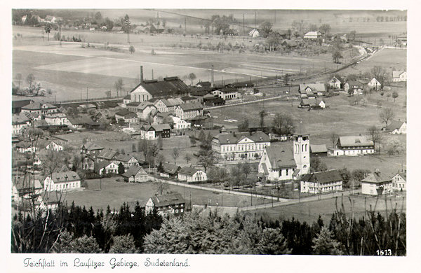 Tato pohlednice z roku 1921 zachycuje střední část obce s kostelem sv. Josefa a za ním stojící školou. V pozadí vidíme dnes již zaniklou sklářskou huť firmy Michel, založenou v roce 1873.