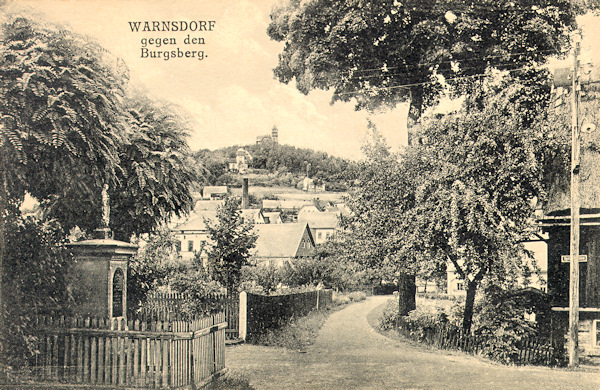 Diese Ansichtskarte zeigt die Strassenkreuzung der heutinen Spital- und Erben-Strasse (Anton Runge-Strasse) im Nordteil der Stadt. Im Hintergrund sieht man die Hrádek-Höhe (Burgsberg) mit ihrem Aussichtsturm.