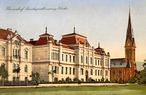 Diese Ansichtskarte zeigt das Gebäude des Bezirksgerichts vom Jahr 1908 in der Gerichtstrasse (heute: Masarykova ulice). Im Hintergrund sieht man die 1904-1905 erbaute evangelische Kirche.
