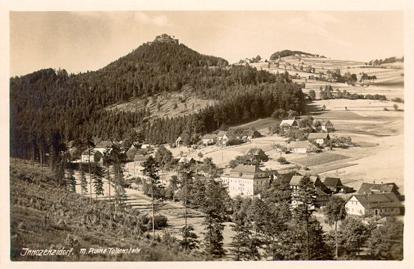 Die Ansichtskarte aus dem Jahre 1929 zeigt das Dorf Lesné (Innozenzidorf) unter der Felsklippe des Tollensteines. In dem heute noch stehenden Gebäude in der Mitte des Bildes bestand früher die Gaststätte „Zum Ritterhof“.