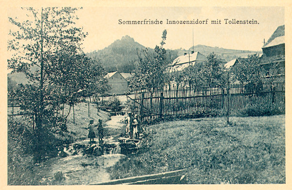 Auf dieser Ansichtskarte aus der ersten Hälfte des 20. Jahrhunderts sieht man den Bach Lesenský potok (Goldflössel), an dem früher die Buschmühle stand. Im Hintergrund ist die Ruine der Burg Tolštejn (Tollenstein).