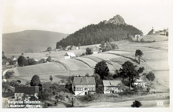 Auf dieser Ansichtskarte aus den 30er Jahren des 20. Jahrhunderts sieht man den oberen Teil der Gemeinde Rozhled (Tollendorf). Rechts von der Felsenklippe mit der Ruine der Burg Tolštejn (Tollenstein) sieht man den noch heute stehenden alten Glockenturm.