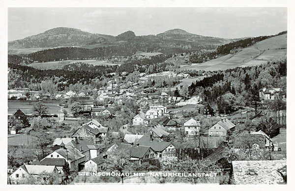 Diese Ansichtskarte bildet den unteren Teil von Kamenický Šenov (Steinschönau) ab. Die Berge im Hintergrund sind von links nach rechts: Studenec (Kaltenberg), Zlatý vrch (Goldberg) und Javorek (Kleiner Ahrenberg).