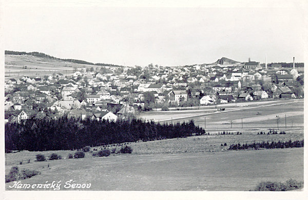 Auf dieser Ansichtskarte sieht man den oberen Teil von Kamenický Šenov (Steinschönau). Aus der Ebene hinter der Stadt ragt der Panská skála (Herrnhausfelsen) heraus und rechts von ihm ist die Vettersche Glashütte.