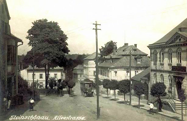 This postcard shows the main road climbing the hill from the town-square to Prácheň. At present the house on the right side is still standing, its extension and two of the houses below it had already been demolished. Instead of them there is a small park.