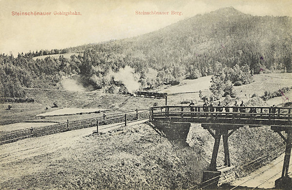 Diese Ansichtskarte zeigt den grossen Bogen der Bahnstrecke hinter dem unteren Bahnhof. Im Hintergrunde der Šenovský vrch (Steinschönauer Berg).