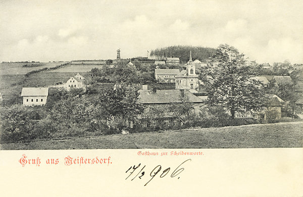 Auf dieser Ansichtskarte vom Jahr 1906 sieht man den oberen Teil von Mistrovice mit der früheren, 1897 erbauten altkatholischen Kirche. Auf der Anhöhe im Hintergrund steht der Aussichtsturm „Scheibenwarte“.