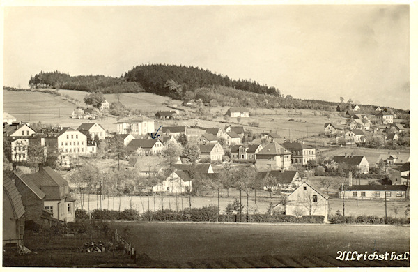 Diese Ansichtskarte zeigt Nový Oldřichov (Ullrichstal) mit dem waldbewachsenen Berge Krásná hora (Vogelsberg). Ganz links sieht man die ehemalige Glashütte und rechts davon im Hintergrund das weisse Schulhaus.