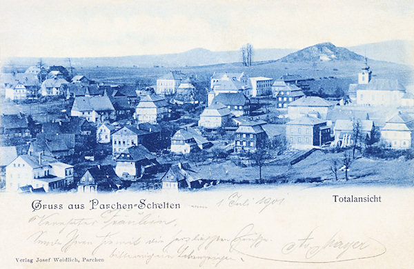 Auf dieser Ansichtskarte von 1901 sieht man den mittleren Teil der Gemeinde mit der St. Laurentiuskirche und den schönen Häusern der hiesigen Glasarbeiter. Im Hintergrund ragt der unscheinbare Hügel des Panská skála (Herrnhausfelsen) hervor.