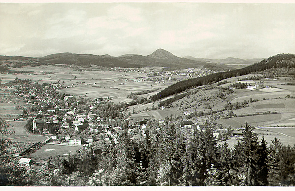 This picture postcard presents the upper part of the village as seen from the Skalický vrch-hill. On the right side rises the Chotovický vrch, behind of which one part of Nový Bor is seen. The horizon is closed by the peaks of the Lusatian Mts with the dominant Klíč.
