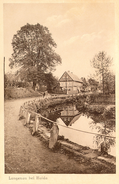 Diese Ansichtskarte aus der Zeit zwischen den Weltkriegen zeigt die am Sporka-Bach unter dem Skalický vrch (Langenauer Berg) entlang führende Gemeindestrasse. Das Haus im Hintergrund steht auch heute noch.