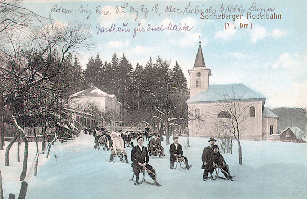 Diese winterliche Ansichtskarte aus dem Jahre 1917 zeigt die Rodelbahn auf der Steinschönauer Strasse, die vom hiesigen Gebirgsverein im Jahre 1909 eröffnet worden ist. Am Walde gegenüber der Kirche steht die Pfarre.