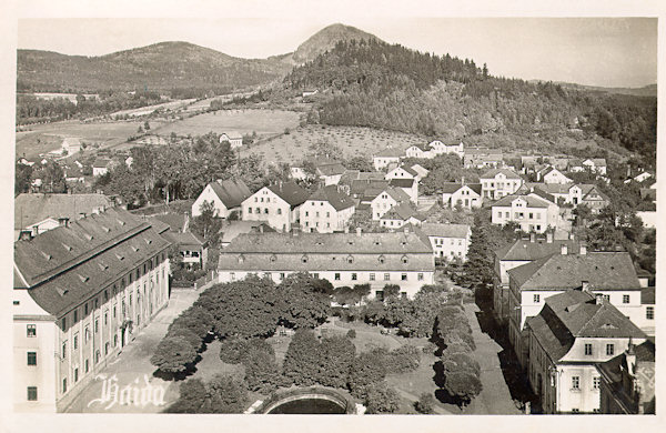 Auf dieser Ansichtskarte aus den Zwischenkriegsjahren sieht man den nördlichen Teil des Stadtplatzes von Nový Bor (Haida) und den anschliessenden Teil von Arnultovice (Arnsdorf) unter dem bewaldeten Borský vrch (Grohmanns Berg), hinter dem am Horizont der spitzige Klíč (Kleis) heraufragt.