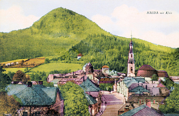 Diese Ansichtskarte aus den 20er Jahren des 20. Jahrhunderts zeigt das Stadtzenztrum mit der von Česká Lípa (B.-Leipa) kommenden Hauptstrasse und der Kirche Mariä Himmelfahrt am Stadtplatz. Im Hintergrund erhebt sich der Berg Klíč (Kleis).