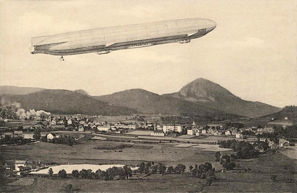 Diese Ansichtskarte wurde 1913 zur geplanten Landung des Zeppelinluftschiffes Sachsen herausgegeben. Wegen der Ungunst des Wetters musste der Flug zweimal verschoben werden und das Luftschiff landete bei Nový Bor erst am 9. November 1913.