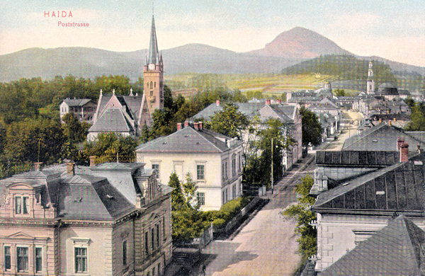 Auf dieser Ansichtskarte aus der Zeit um 1905 sieht man die damalige Poststrasse von Süden. Im Vordergrund steht die 1902 erbaute evangelische Kirche, im Hintergrund ragt der Turm der Kirche Mariä Himmelfahrt empor und den Horizont hinter der Stadt schliesst der monumentale Kegel des Klíč-Berges (Kleis) ab.