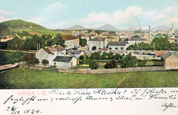 Diese Ansichtskarte aus der Zeit um 1920 zeigt die um den Bahnübergang am Nordende des Bahnhofs stehenden Häuser. Im Hintergrund rechts sieht man die Mariä Himmelfahrtskirche, links erhebt sich der Borský vrch (Grohmanns Höhe).