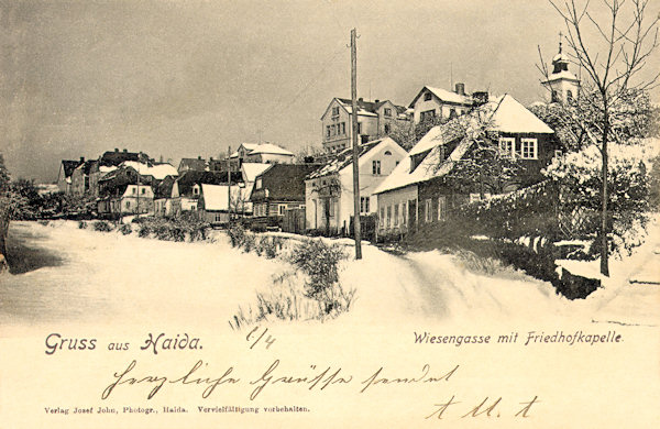 Diese Ansichtskarte von 1920 zeigt die damalige Wiesengasse (Heute Winterova ulice), die bis heute fast unverändert geblieben ist. Im Hintergrund rechts ragt der Turm der Friedhofskapelle empor.