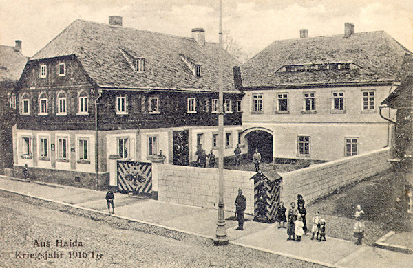 Diese Ansichtskarte zeigt aus dem Jahr 1917 zeigt das ehemalige Haus No. 20 in der damaligen Poststrasse (heute Masarykova ulice), in dem sich die Kommandantur der Garnison Nový Bor befand. In den 70er Jahren des 20. Jahrhunderts wurde es zusammen mit den Nachbarhäusern abgerissen und durch Grossblockbauten ersetzt.