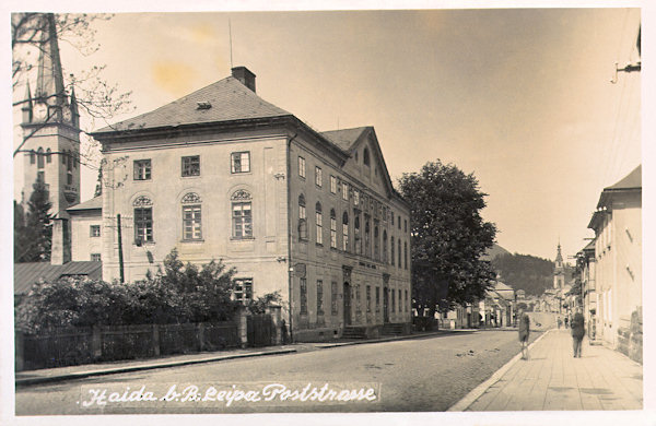Auf dieser Ansichtskarte vom Ende der 30er Jahre des 20. Jahrhunderts sieht man die ehemalige Lüsterfabrik der Gebrüder Palme in der T. G. Masaryk-Strasse (Poststrasse), und den hinter ihr heraufragenden Turm der evangelischen Kirche.
