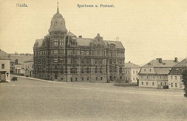 Na této pohlednici vidíme jihozápadní roh náměstí s výstavnou secesní budovou pošty a spořitelny, otevřenou v létě roku 1904. Ozdobná kopule věže musela být koncem 30. let odstraněna.