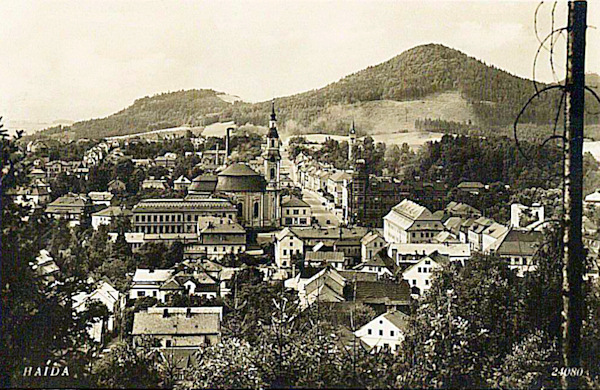 Na pohlednici ze začátku 30. let 20. století vidíme střed města s kostelem Nanebevzetí Panny Marie a hlavní ulicí, vedoucí do České Lípy. V pozadí je Chotovický vrch.