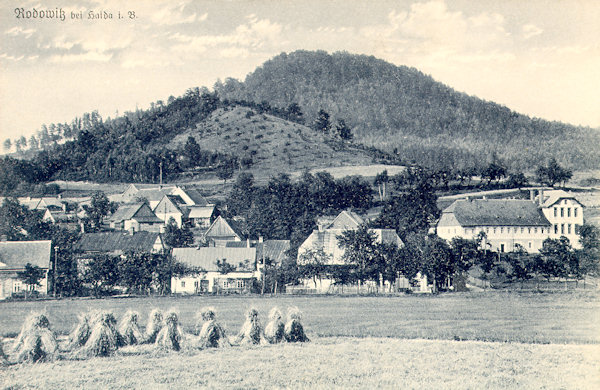 Diese Ansichtskarte von Anfang des 20. Jahrhunderts zeigt das Niederdorf mit dem auffallenden Gebäude der Schule (rechts). Hinter dem Dorf steigt der Pomahačův vrch empor und den Horizont hinter ihm schliesst der Strážný (Wachberg) ab.