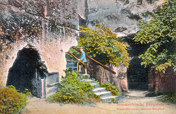 Diese Ansichtskarte zeigt den gegenwärtig nicht zugänglichen Felsenhof an der Nordseite des Poustevnický kámen (Einsiedlerstein). Zwischen den Öffnungen der in den Felsen gehauenen Räume führen Stufen zu der in einen engen Felsspalt gehauenen Rittertreppe, die auf den Gipfel des Felsens führt.